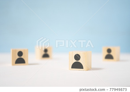 Wooden toy cubes with painted men stand apart from each other. 77949873