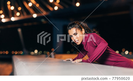 Sportswoman doing push-ups near embankment at night Sportswoman doing push-ups near embankment at night 77950020