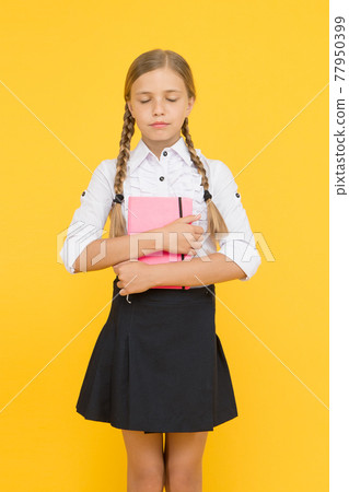 Literature for school. Adorable little girl with closed eyes holding book of English literature  77950399