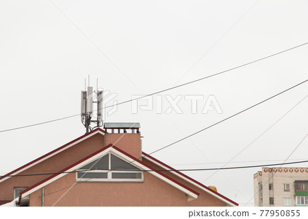 Telecommunication antenna next to the chimney on the roof of the house Telecommunication antenna next to the chimney on the roof of the house 77950855