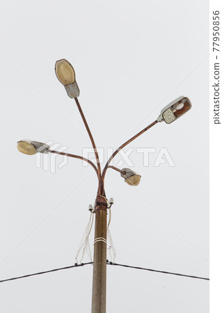 A pillar of street lighting with several lanterns against a gray sky. A pillar of street lighting with several lanterns against a gray sky. 77950856