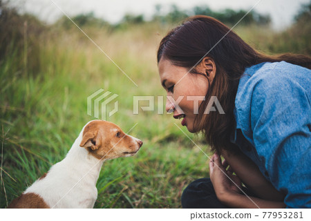 Happy cheerful hipster girl playing with her dog in the park during sunset. Vintage of young woman with her dog. 77953281