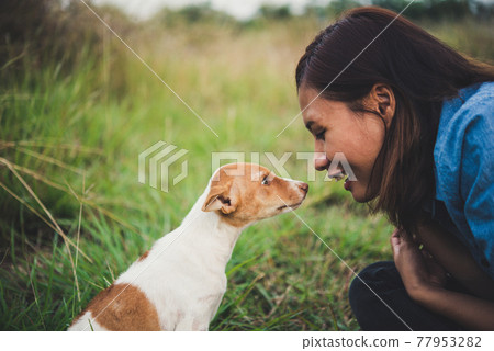 Happy cheerful hipster girl playing with her dog in the park during sunset. Vintage of young woman with her dog. Happy cheerful hipster girl playing with her dog in the park during sunset. Vintage of young woman with her dog. 77953282