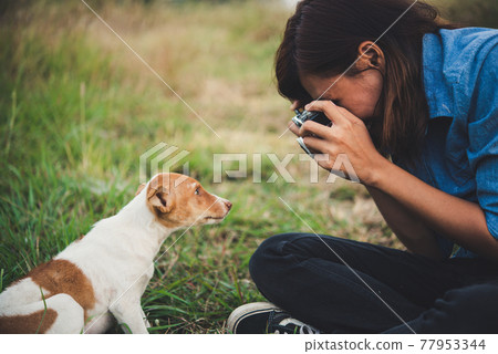 Happy cheerful hipster girl playing with her dog in the park during sunset. Vintage of young woman with her dog. Happy cheerful hipster girl playing with her dog in the park during sunset. Vintage of young woman with her dog. 77953344