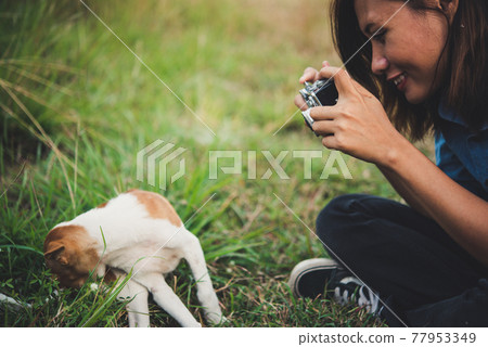 Happy cheerful hipster girl playing with her dog in the park during sunset. Vintage of young woman with her dog. Happy cheerful hipster girl playing with her dog in the park during sunset. Vintage of young woman with her dog. 77953349