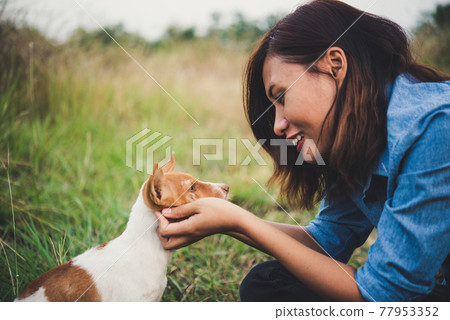 Happy cheerful hipster girl playing with her dog in the park during sunset. Vintage of young woman with her dog. Happy cheerful hipster girl playing with her dog in the park during sunset. Vintage of young woman with her dog. 77953352