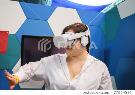 Woman gesturing in virtual reality headset Woman gesturing in virtual reality headset 77954585