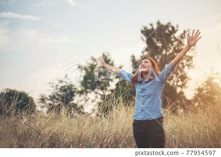 Beautiful woman hipster raising her arm in the air with bouquet and having fun in summer field during sunset. Beautiful woman hipster raising her arm in the air with bouquet and having fun in summer field during sunset. 77954597