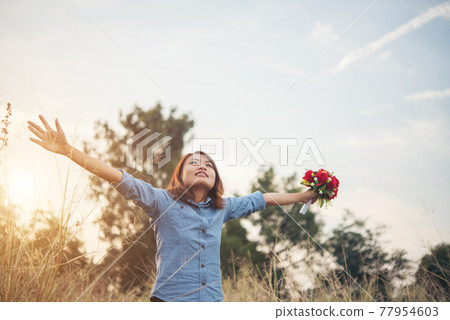 Beautiful woman hipster raising her arm in the air with bouquet and having fun in summer field during sunset. Beautiful woman hipster raising her arm in the air with bouquet and having fun in summer field during sunset. 77954603