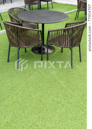 outdoor table set. Placed on an artificial green grass, table set for dining decorating with artificial grass circle shape on the floor. outdoor table set. Placed on an artificial green grass, table set for dining decorating with artificial grass circle shape on the floor. 77954707