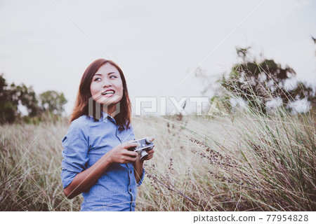 Happy young hipster woman with vintage camera in field. Enjoy with nature sunset, Vintage hipster woman photographer. Happy young hipster woman with vintage camera in field. Enjoy with nature sunset, Vintage hipster woman photographer. 77954828