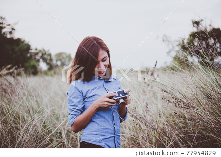 Happy young hipster woman with vintage camera in field. Enjoy with nature sunset, Vintage hipster woman photographer. Happy young hipster woman with vintage camera in field. Enjoy with nature sunset, Vintage hipster woman photographer. 77954829