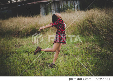 Young beautiful woman enjoying nature in field. Woman raising her arm up in the air enjoy with mature. Women lifestyle with vintage filter. Young beautiful woman enjoying nature in field. Woman raising her arm up in the air enjoy with mature. Women lifestyle with vintage filter. 77954844