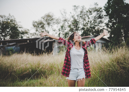 Young beautiful woman enjoying nature in field. Woman raising her arm up in the air enjoy with mature. Women lifestyle with vintage filter. 77954845