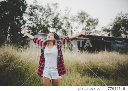 Young beautiful woman enjoying nature in field. Woman raising her arm up in the air enjoy with mature. Women lifestyle with vintage filter. Young beautiful woman enjoying nature in field. Woman raising her arm up in the air enjoy with mature. Women lifestyle with vintage filter. 77954846
