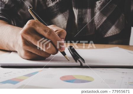Young businessman writes in a notebook while working analysis business data in office. Young businessman writes in a notebook while working analysis business data in office. 77955671