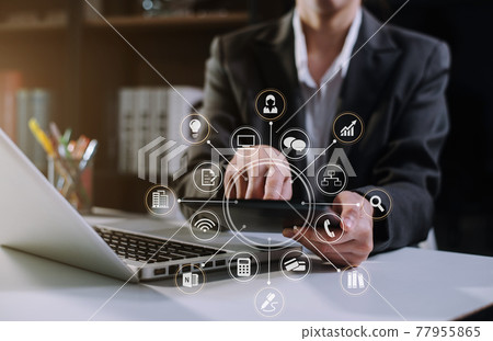 Designer using tablet with laptop and document on desk in modern office. 77955865