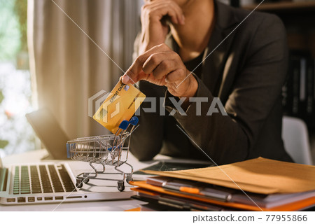 Businessman use credit card to shopping online in internet website shop with computer laptop on work table in office. Businessman use credit card to shopping online in internet website shop with computer laptop on work table in office. 77955866