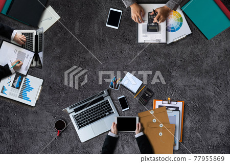 Top view of businessman Group of Multiethnic Busy People meeting with other in modern office with laptop computer, smartphone, tablet, coffee and document on table. 77955869