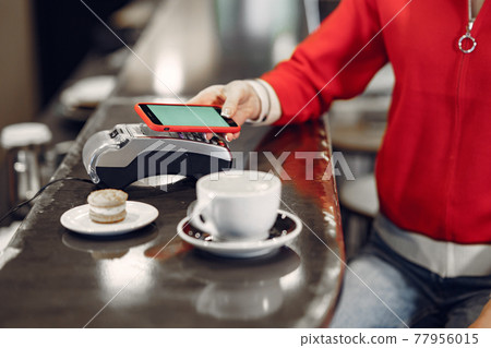 Girl paying for her latte with a smartphone by contactless PAY PASS technology 77956015