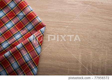 Checkered red and white napkin on wooden background. Checkered red and white napkin on wooden background. 77956572