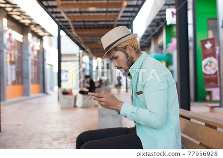 Handsome hipster young man with white headphones outside in the town. Chilling out. 77956928