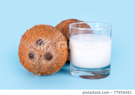 Coconuts and a glass of coconut milk on blue background. Healthy vegan food, lactose free diet, milk alternative 77958481