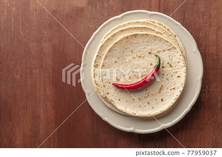 A red chilli pepper, shot from the top on a pile of tortillas, Mexican flatbreads 77959037
