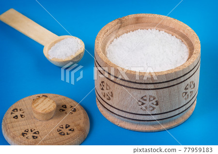 Salt in a wooden salt shaker on blue background Salt in a wooden salt shaker on blue background 77959183