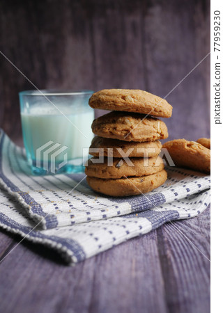 stack of whole meal cookies and glass of milk on wooden background stack of whole meal cookies and glass of milk on wooden background 77959230