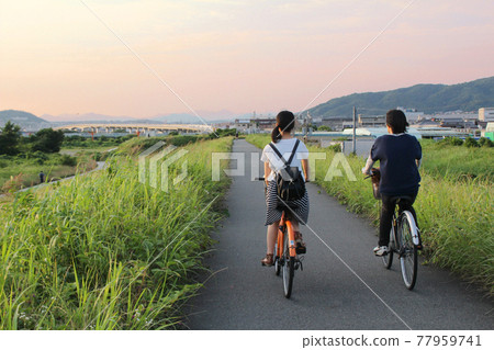 夕陽岸邊騎自行車的女孩 77959741