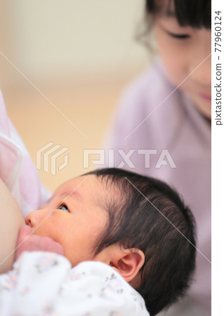 Sister watching mom breastfeeding newborn baby 77960124