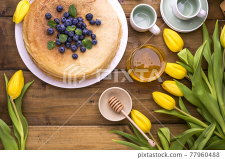 Large traditional Russian pancakes with berries and honey on a wooden table. Baking for the spring Large traditional Russian pancakes with berries and honey on a wooden table. Baking for the spring 77960488