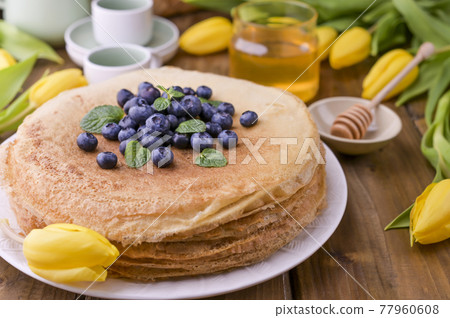 Large traditional Russian pancakes with berries and honey on a wooden table. Baking for the spring 77960608