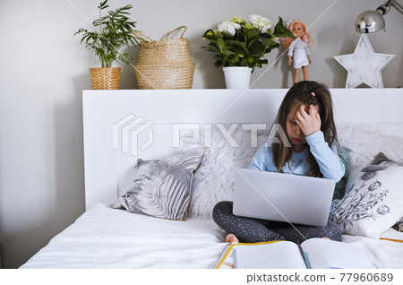 Pretty schoolgirl studying homework her online lesson at home, social distance during quarantine 77960689