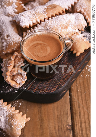 Carnival food TYPICAL and aromatic coffee. Sfrappole or chiachiere or angel wings on a woody Carnival food TYPICAL and aromatic coffee. Sfrappole or chiachiere or angel wings on a woody 77960776