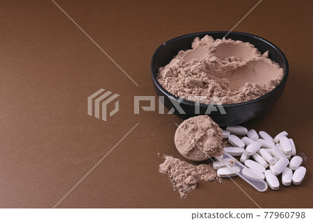 Sports nutrition on a black background. Protein and dietary supplements in powder and in tablets 77960798