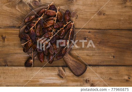 Juicy dates on a wooden table. Dried fruits for a healthy diet. Juicy dates on a wooden table. Dried fruits for a healthy diet. 77960875