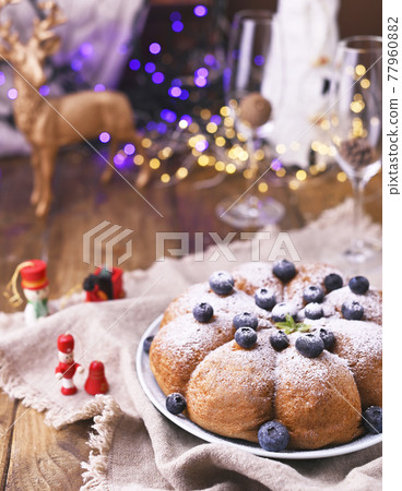 Christmas cake with berries and icing sugar on a wooden background. Christmas cake with berries and icing sugar on a wooden background. 77960882
