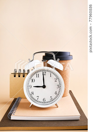White alarm clock with arrows at nine in the morning and stationery made from recyclable material White alarm clock with arrows at nine in the morning and stationery made from recyclable material 77960886