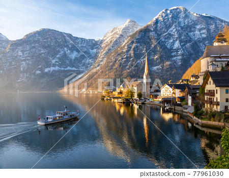 VIew of beautiful Hallstatt lake and famous church during morning sunrise in early spring VIew of beautiful Hallstatt lake and famous church during morning sunrise in early spring 77961030