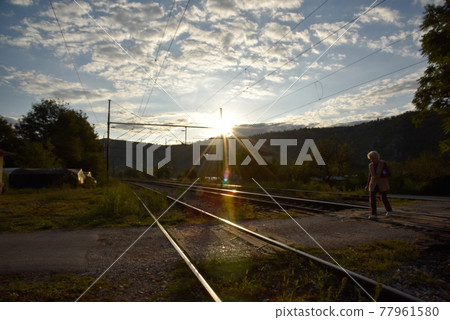 夕陽西下，一名女子穿越鐵路。 77961580