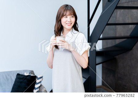 Woman relaxing in the living room with coffee Woman relaxing in the living room with coffee 77963282