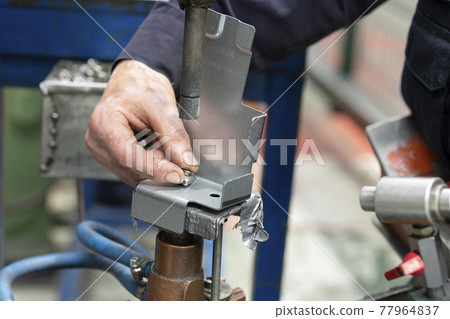 Close up of a metal element being spot-welded by a factory worker. Industry concept. 77964837