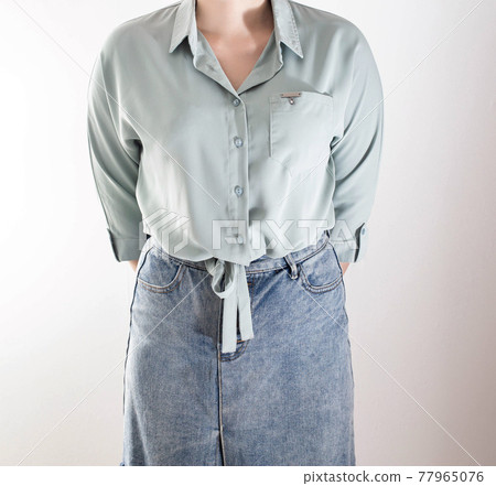 Stylish girl in a blouse with ties at the bottom and a denim skirt on a white background. Shopping and business lady concept, top Stylish girl in a blouse with ties at the bottom and a denim skirt on a white background. Shopping and business lady concept, top 77965076