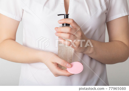 The girl holds in her hands a silicone brush for cleaning the face and gel mousse for skin care, dermatology The girl holds in her hands a silicone brush for cleaning the face and gel mousse for skin care, dermatology 77965080