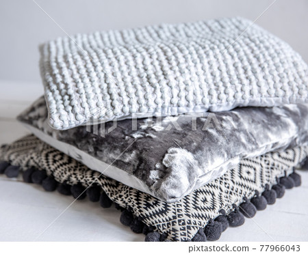 Close up of stylish textured pillows stacked in a stack. 77966043