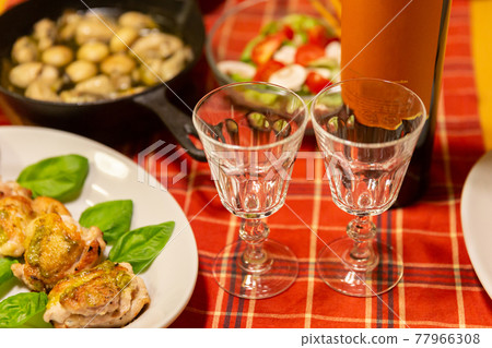 Two wine glasses lined up on the table and cooking at home 77966308