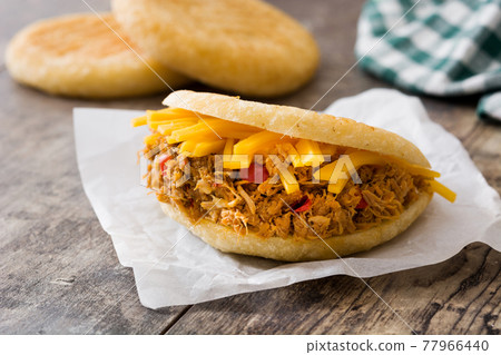 Arepa with shredded beef and cheese on wooden background. 77966440