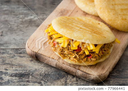 Arepa with shredded beef and cheese on wooden background. Arepa with shredded beef and cheese on wooden background. 77966441